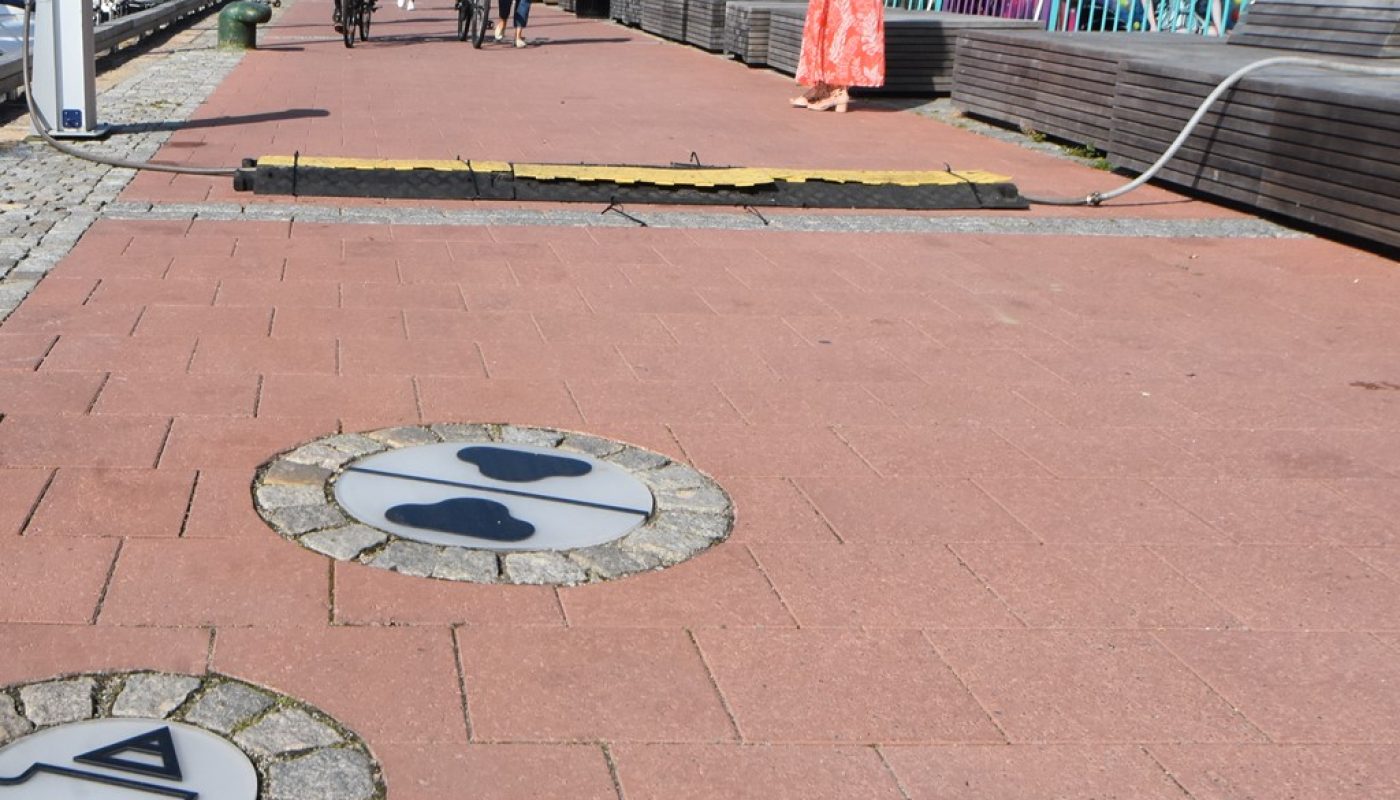 Selve bryggepromenaden er hellelagt med rustrød heller, og med symboler fra skipsfarten. Symbolene går også igjen i den nye gata.
